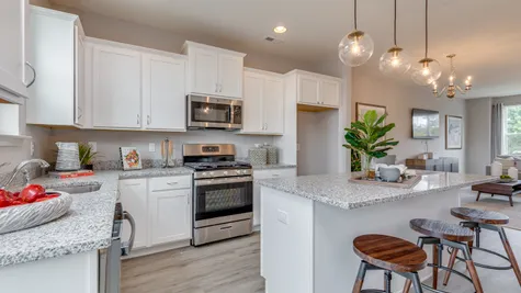 New townhome kitchen with white cabinets, stainless steel appliances, and center island with granite countertop.