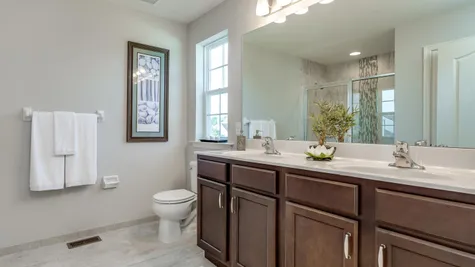 The Laurelton bathroom with double sinks in vanity, large mirror with lights above.