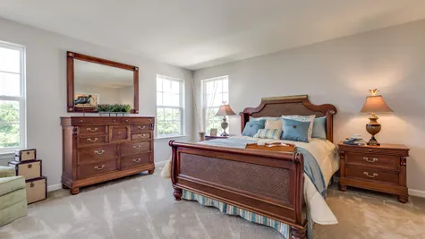The Laurelton master bedroom with carpet, 3 windows, sample furniture.