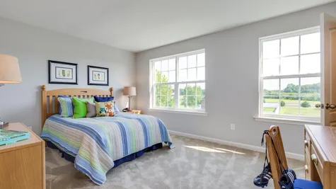 Bedroom in The Laurelton decorated with sample furniture for a child, with carpet & windows.