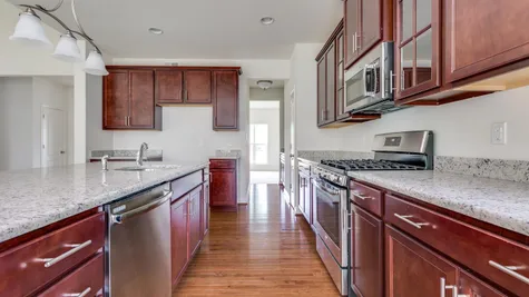 Augusta kitchen with brown cabinets and central island, stainless steel appliances, wood floor.