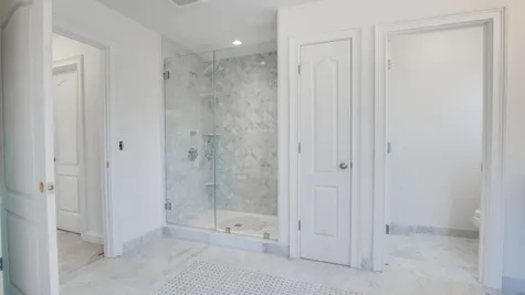 Shower in Brandywind master bathroom with decorative tile and glass doors.