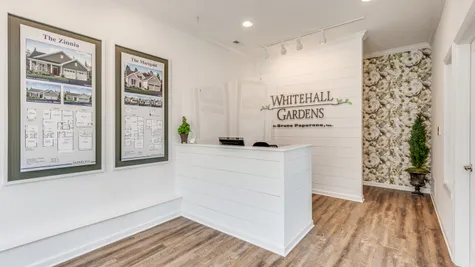 The Whitehall Garden logo is large behind the sales office desk with displays of the models on the adjacent walls.