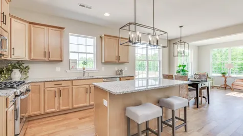 A lovely kitchen with light wood cabinets, a large center island and is adjacent to a eat-in kitchen space with table and 4 chairs