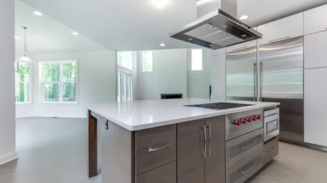 The Stoneleigh kitchen with large center island in foreground, large Subzero refrigerator to left, stainless steel exhaust hood.