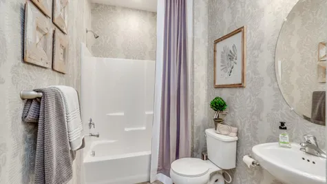 Hall bathroom in Zinnia model new home with pedestal sink and shower over tub.