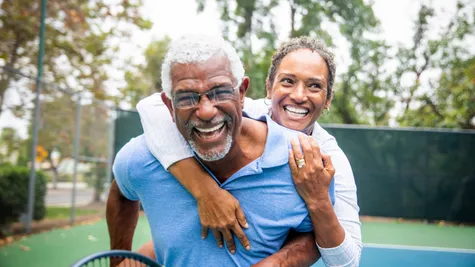 A happy active adult couple playing a game of pickleball on a beautiful sunny day