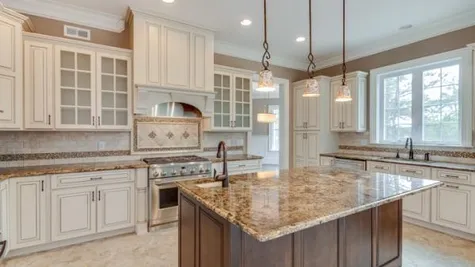 Stoneleigh Kitchen center island, pendant lights over island, tile floor, granite counters, light color cabinets - some glass.
