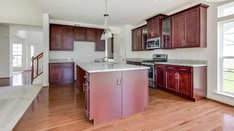Augusta kitchen with brown cabinets and central island, stainless steel appliances, wood floor.