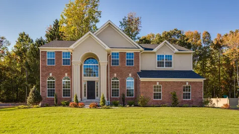Exterior of the Baldwin Traditional model luxury new home in south NJ with brick front and soaring 2 story columns and transom windows.