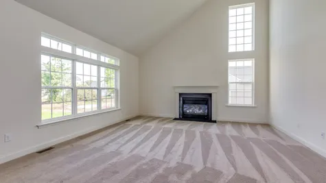 Wexford model new home in South New Jersey family room with optional fireplace, sloping high ceiling, carpet, large windows.
