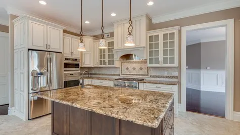 Stoneleigh Kitchen center island, pendant lights over island, tile floor, granite counters, light color cabinets - some glass.