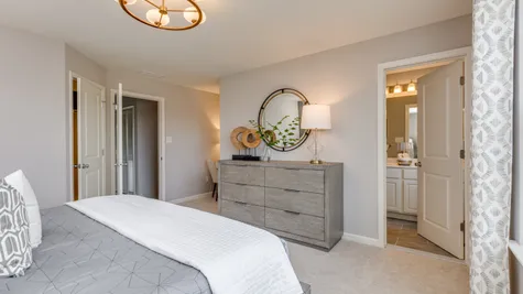 Owner's bedroom with grey wood dresser and gold accent decor throughout the room.
