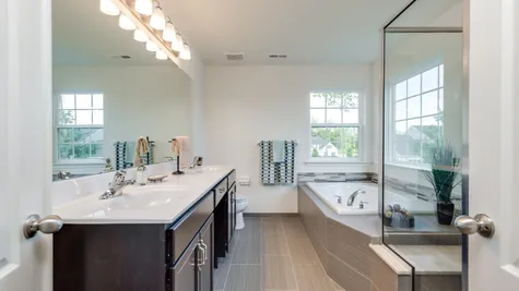 Wexford master bathroom with double sink vanity, soaking tub, windows, walk-in shower with glass enclosure.