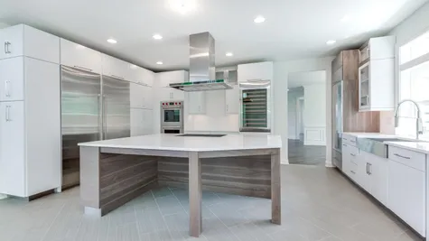 The Stoneleigh kitchen with large center island in foreground, large Subzero refrigerator to left, stainless steel exhaust hood.