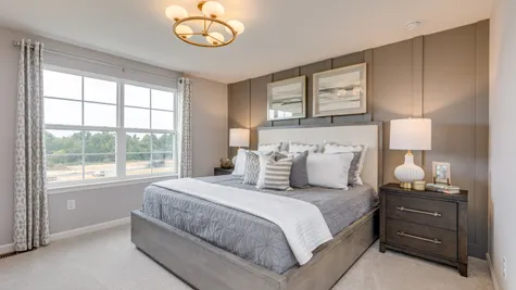 Owner's bedroom with wood plank accent wall painted in a beautiful grey color behind the king size bed.