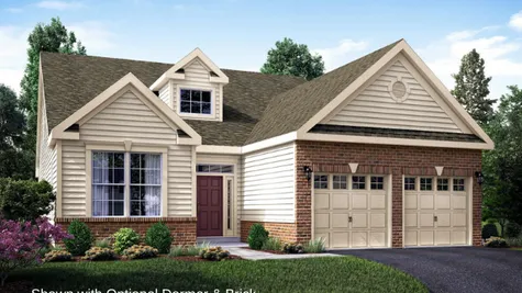 The Marigold Manor one story active adult home in NJ with brick surrounding 2 garage doors, tan siding and colonial trim.