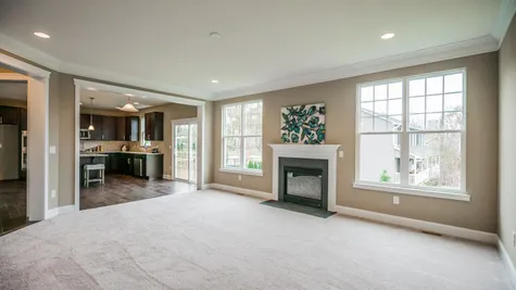 Oakton Family room with wall to wall carpet, optional fireplace, large double windows to either side, kitchen in background.