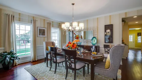Formal dining room in Brandywine model home with wood floors, two large windows, chandelier and sample furniture.