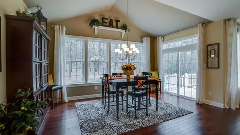 Eating area next to kitchen in Brandywine model new home with sliding doors to outside, wood floors, chandelier.