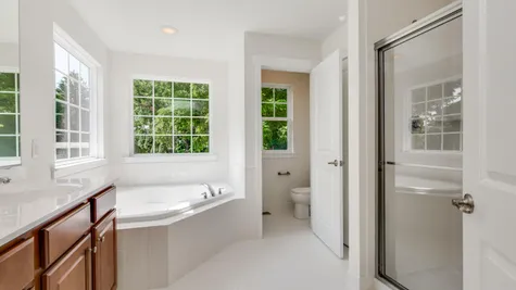 The Ashton Hall bathroom on second floor with soaking tub, shower, double sink and wood cabinets.
