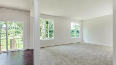 Family Room of the Ashton model home with many windows, white walls, pale carpet.