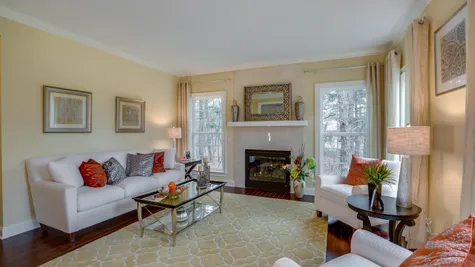 Formal living room with fireplace and large windows, wood floors in Bandywine model new home.