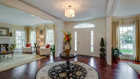 Front hall and door of Brandywine new luxury home in NJ with wood floors, sample decor, living room to left, dining room on right.