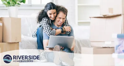 Image of a woman hugging her partner while he looks at a laptop.