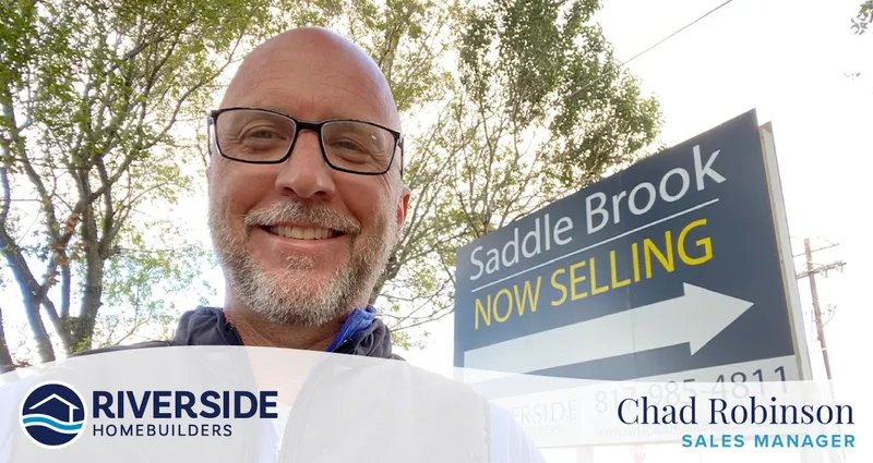 Image of Chad Robinson in front of Saddle Brook's community sign that says "Now Selling"