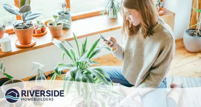 Image of a woman surrounded by her houseplants and looking at her phone.