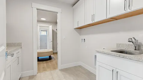 laundry room has extra storage and a utility sink and opens to both the hallway and the primary bedroom closet