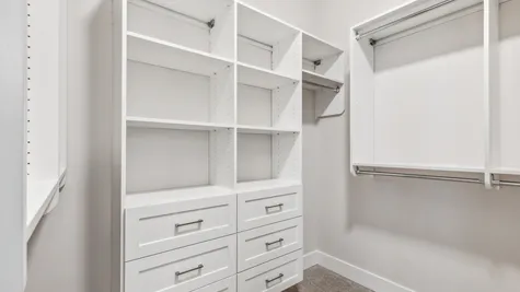 Custom designed built-ins in primary closet with rods, shelves and drawers built in