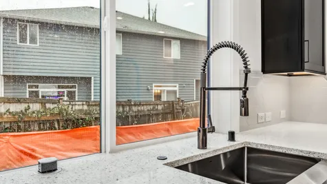 farmhouse sink and touchless faucet framed by large kitchen window
