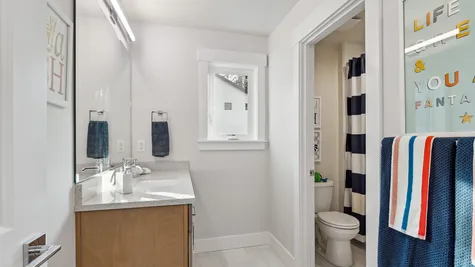 bathroom between two bedrooms has two vanities and a separate water closet with toilet and tub/shower combo