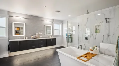 primary bathroom with a wall of tile behind floating vanity, tile floors, freestanding soaking tub and walk-in shower with dual showerheads