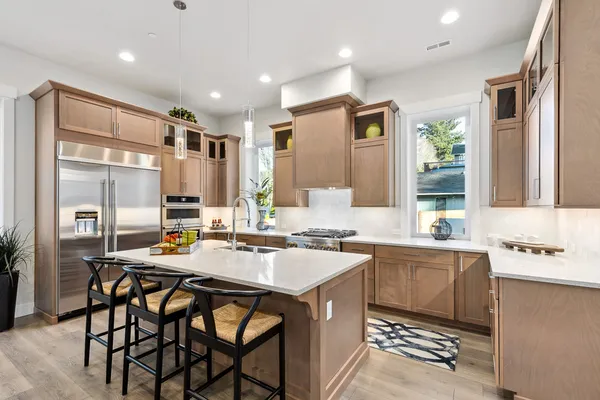 kitchen with wood cabinets, kitchen island, slab quartz countertops, Jenn Air Rise appliances