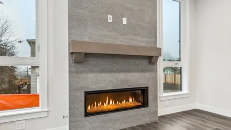 contemporary gas fireplace with full-height tile surround and wood mantel, flanked by two windows, also has tv outlets above fireplace