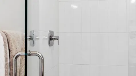 Fully tiled shower and frameless door in main level bath