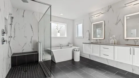 fully tiled primary bathroom; walk-in shower with bench and dual showerheads; freestanding soaking tub