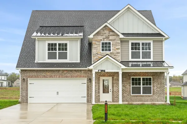 Front exterior of The Brayden by Rockwood Homes, a two-story home with stone and tan siding and a two-car garage.