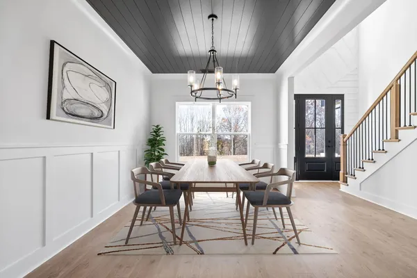 The Smokey dining room staged with a table and chandelier under a dark wood ceiling panel