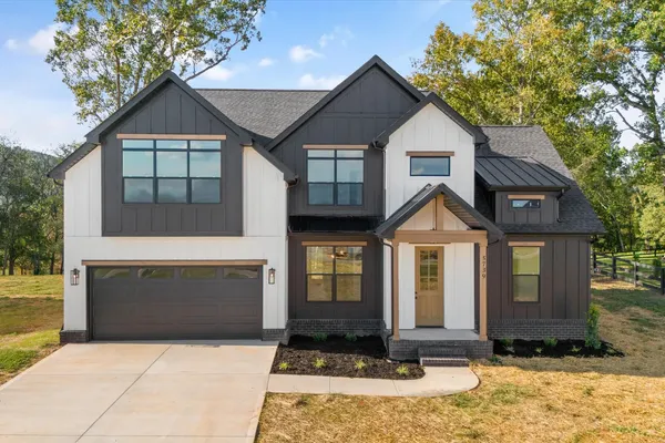 Front exterior of The Smokey by Rockwood Homes, a two-story home with white siding, black trim, and a black garage door.