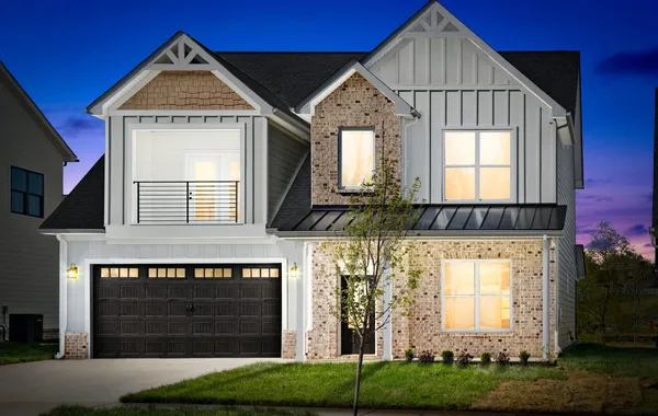 Front exterior of The Odie by Rockwood Homes, a two-story home with white board and batten siding and a black garage door.