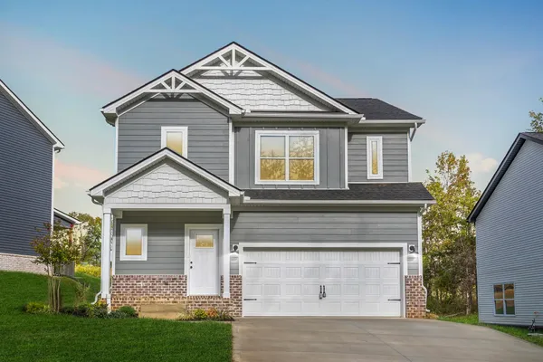 Front exterior of The Maui by Rockwood Homes, a two-story home with gray siding, stone accents, and a two-car garage.