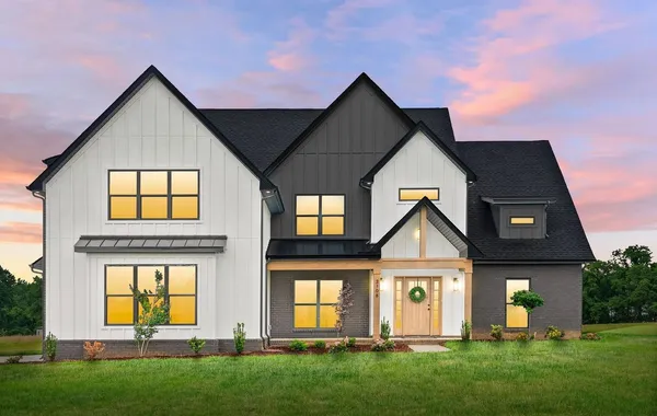 The Aspen Ridge exterior at dusk with white siding, black gables, and wood front door