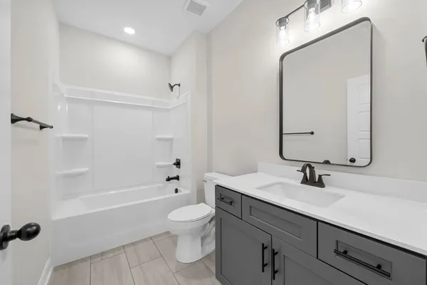 The Cumberland bathroom with a dark gray vanity, a black-framed mirror, and a tub and shower combination