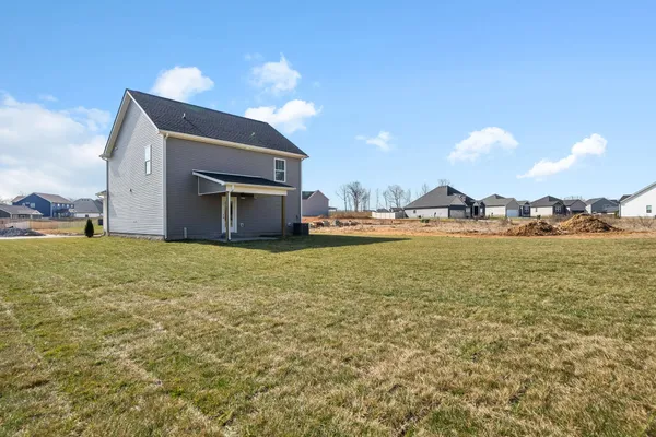 Side exterior of The Maui by Rockwood Homes, a two-story home with gray siding on a wide lot.
