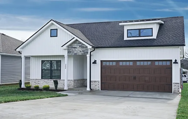 The Bayshore exterior with white board and batten siding, stone porch gable, and wood-tone garage door