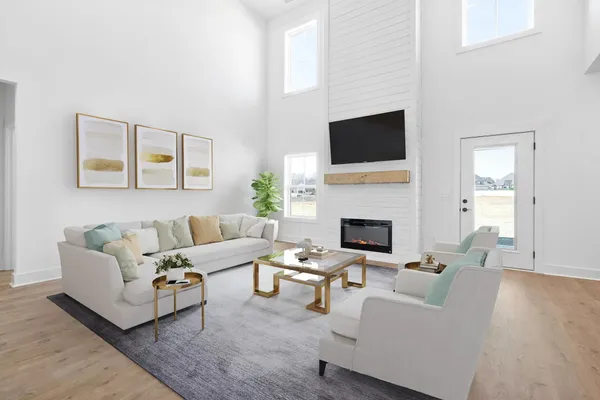 The Smokey living room staged with a sectional under a two-story ceiling with tall windows